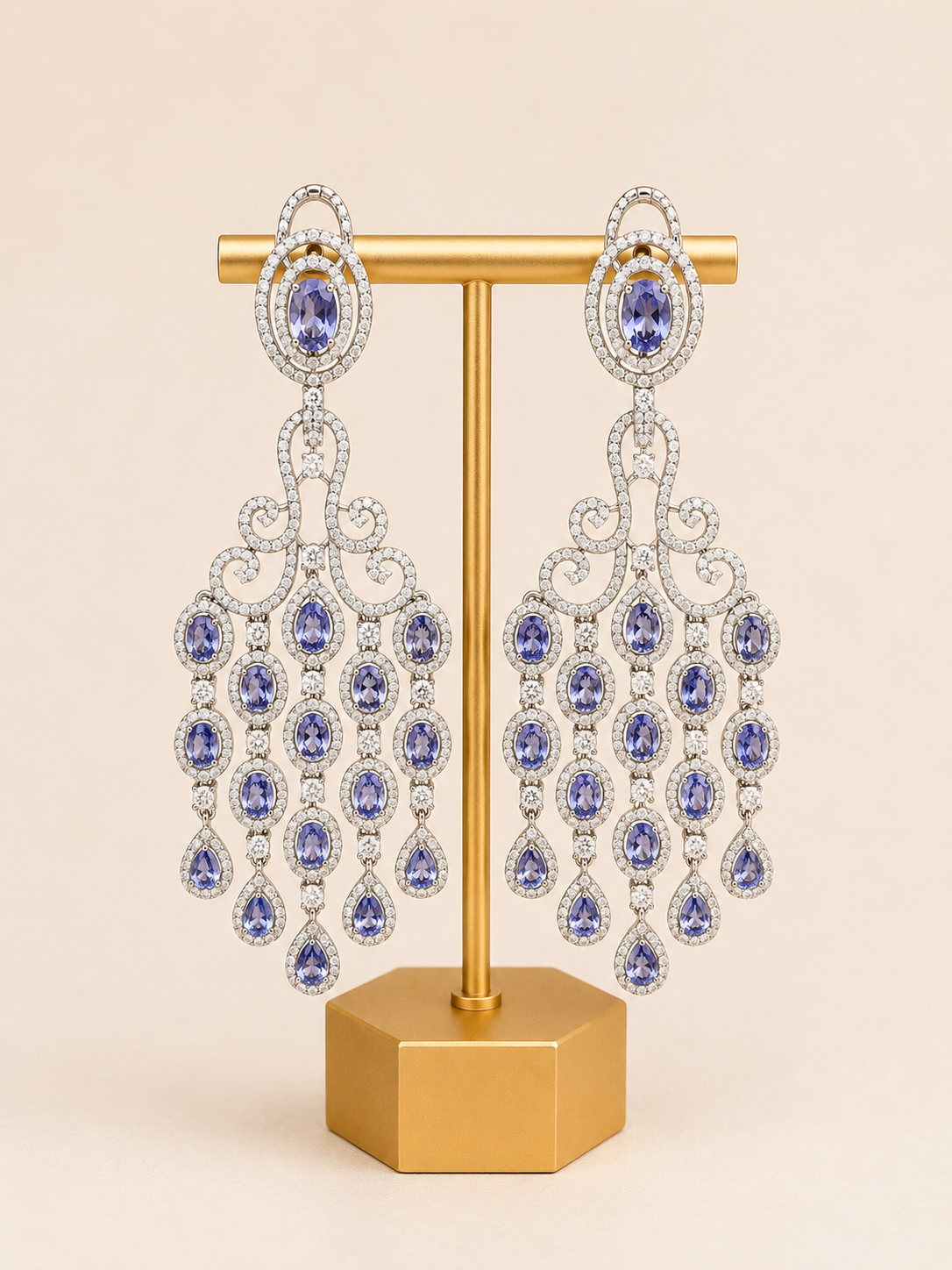 Pair of ornate earrings with purple gemstones on a gold stand against a beige background