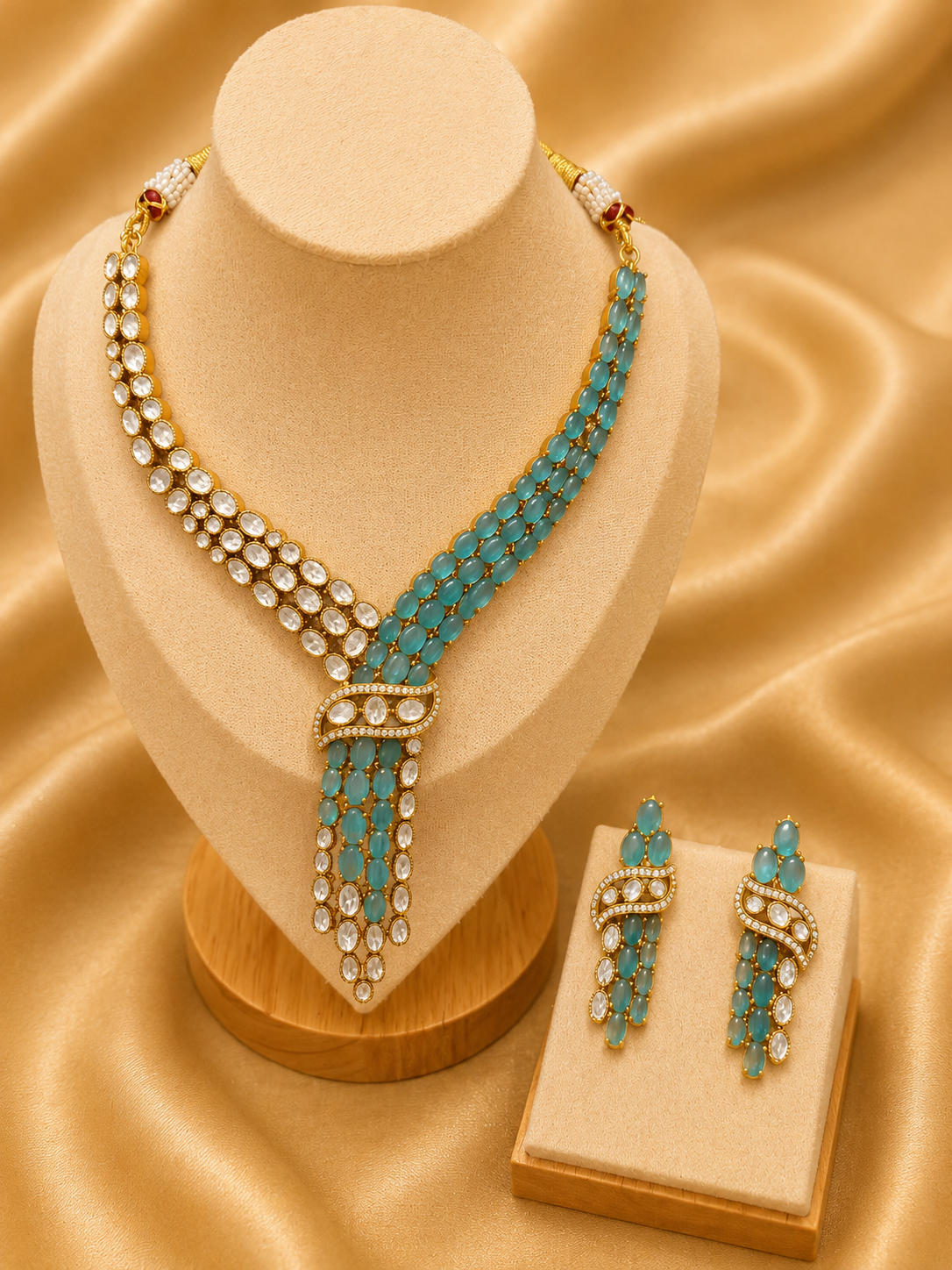 Turquoise and gold necklace and earrings on a beige stand with a matching box on a beige fabric background