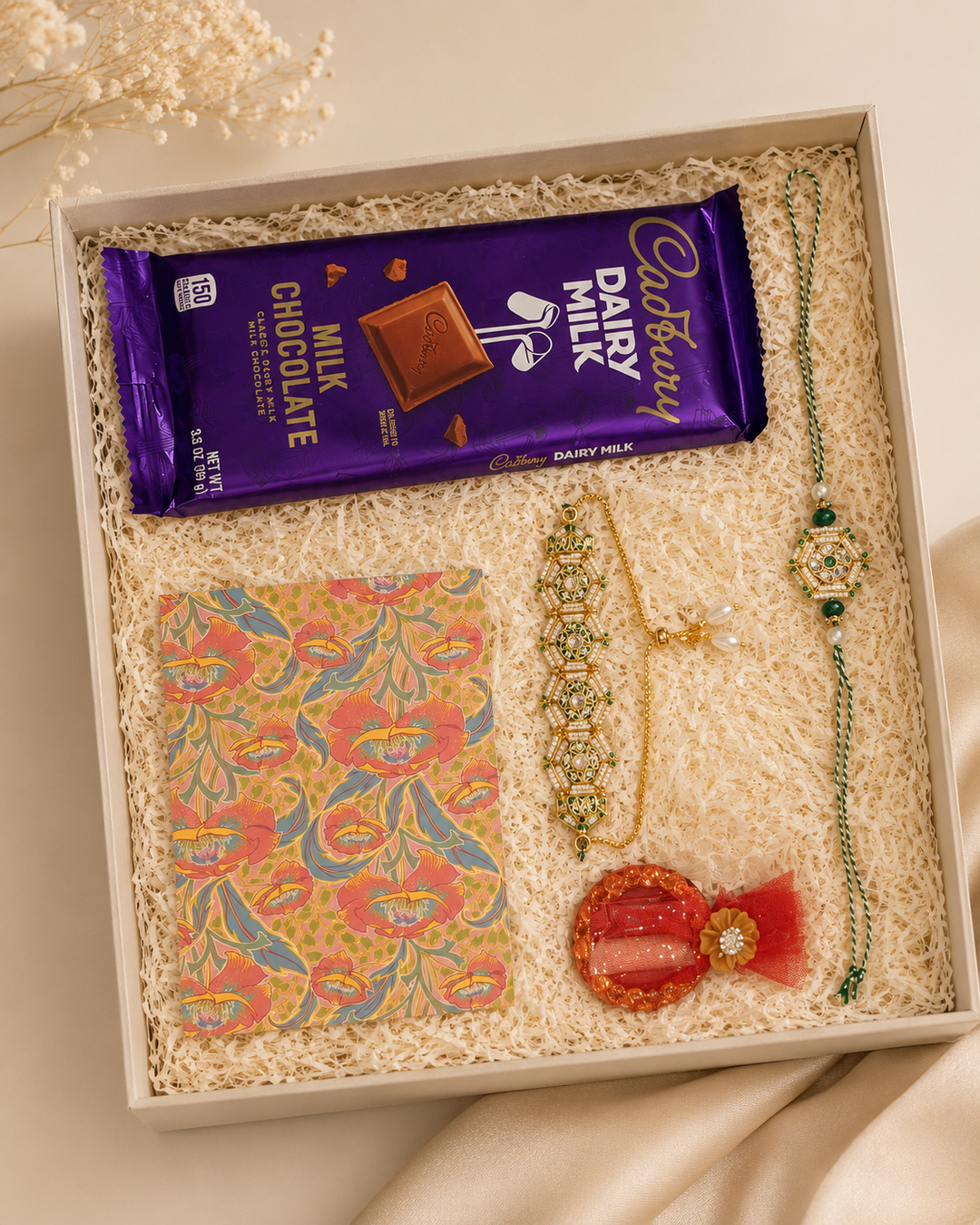 Emerald Regal Raksha Bandhan gift set with green rakhi, lumba, chocolate, greeting card, and roli.