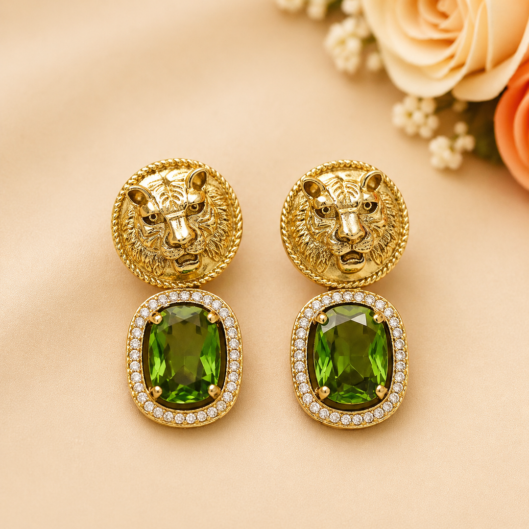 Gold earrings with green gemstones on a beige background