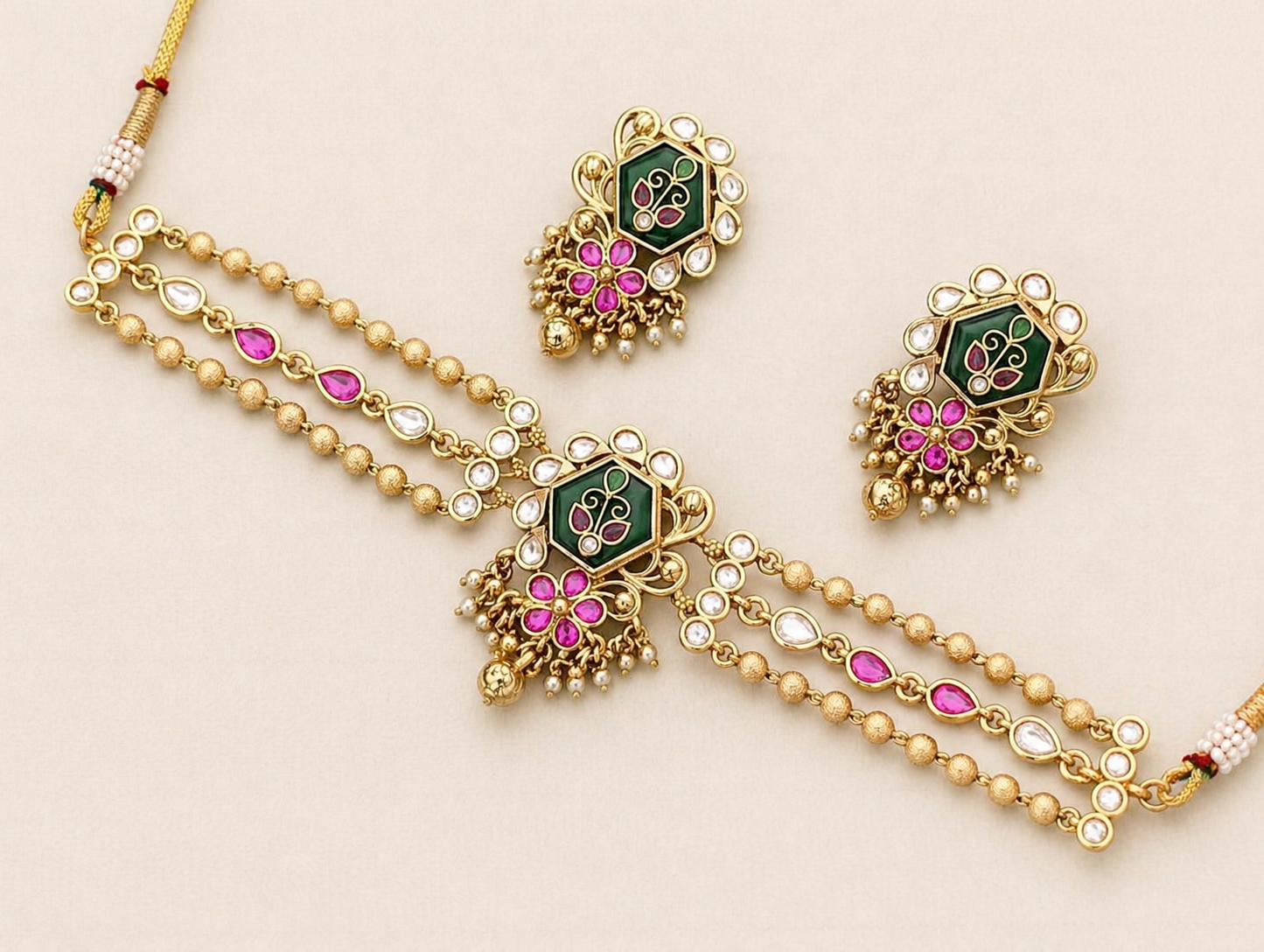 Gold necklace with pink and green gemstones on a beige background