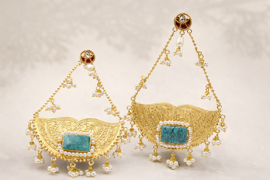 Gold earrings with turquoise stones and pearl accents on a light background