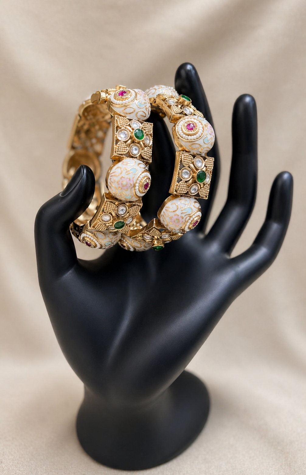 Traditional gold bangles with circular ivory motifs and red stone accents, close-up view