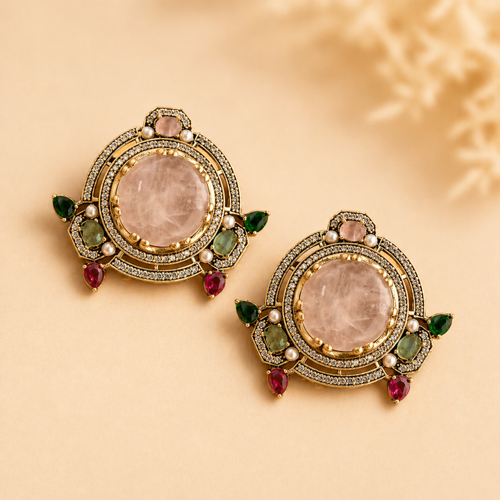 Pair of ornate earrings with gemstones on a beige background