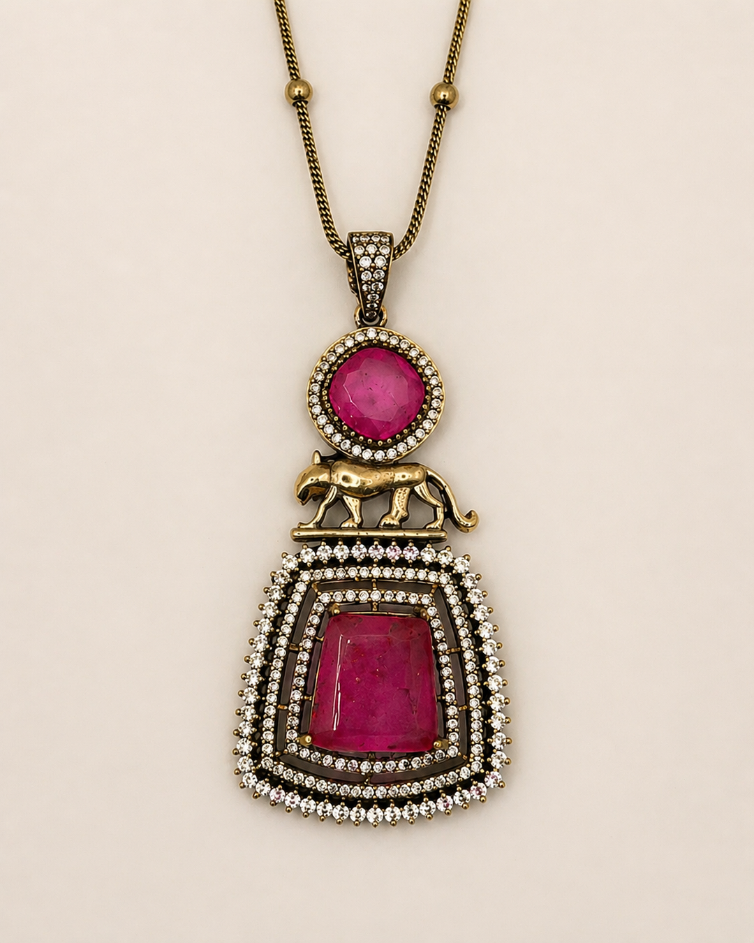 Necklace with a pendant featuring red stones and gold accents on a beige background