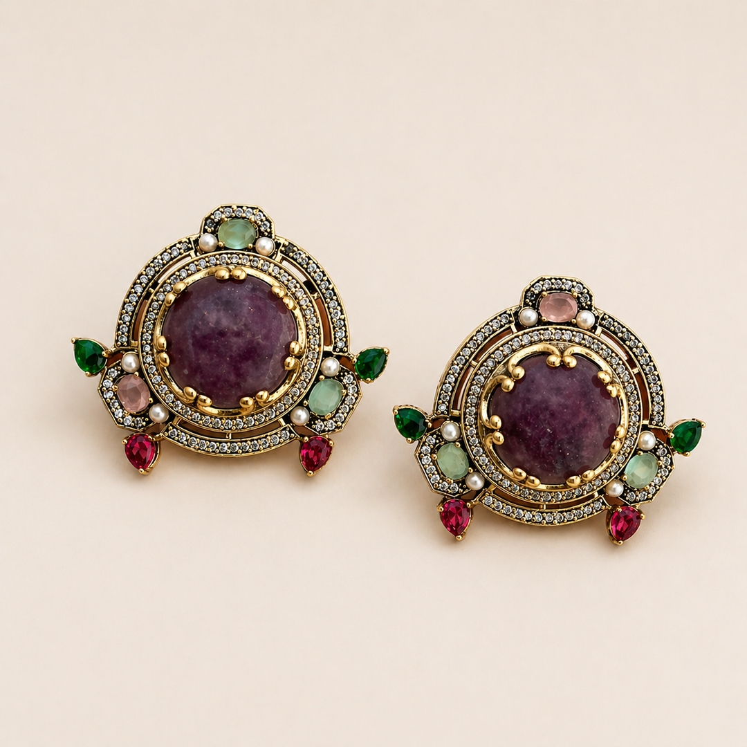 Pair of ornate earrings with gemstones on a beige background