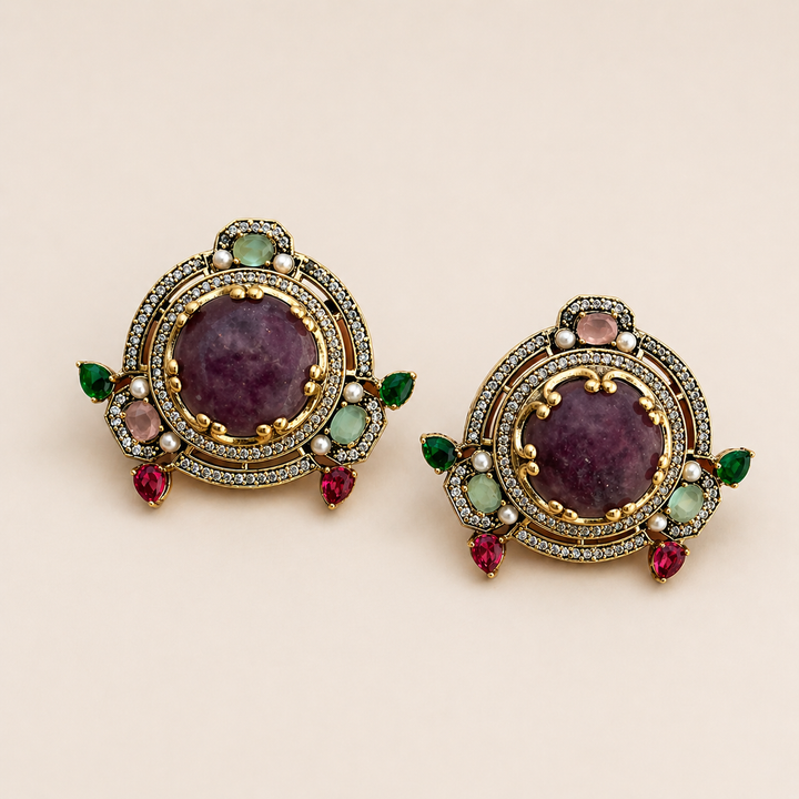 Pair of ornate earrings with gemstones on a beige background