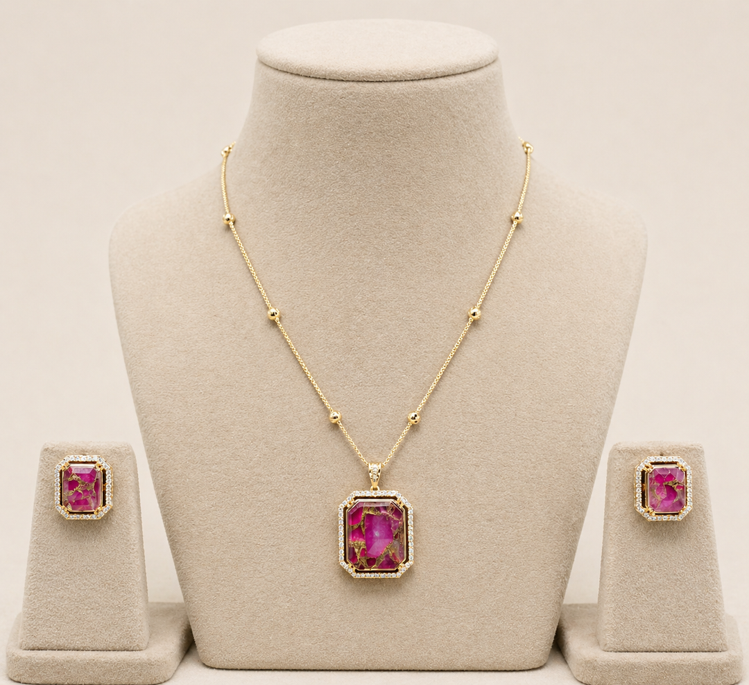 Gold necklace with pink gemstones on a mannequin bust, accompanied by matching earrings.