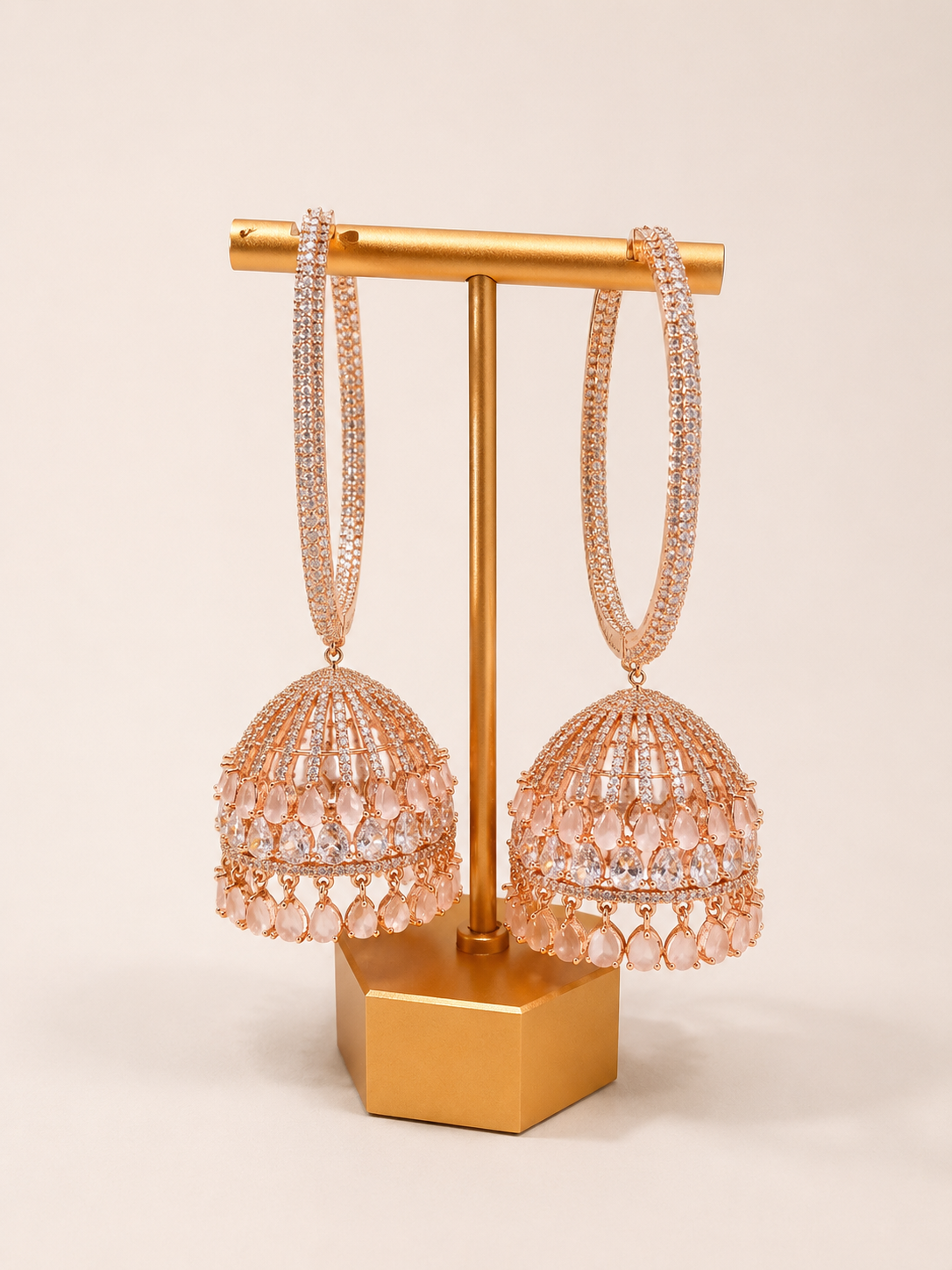 Pair of pink beaded earrings on a gold stand against a beige background