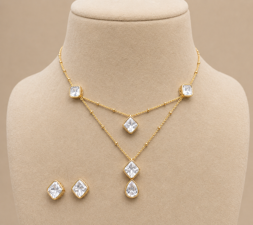Gold necklace and earrings set on a mannequin bust with a beige background