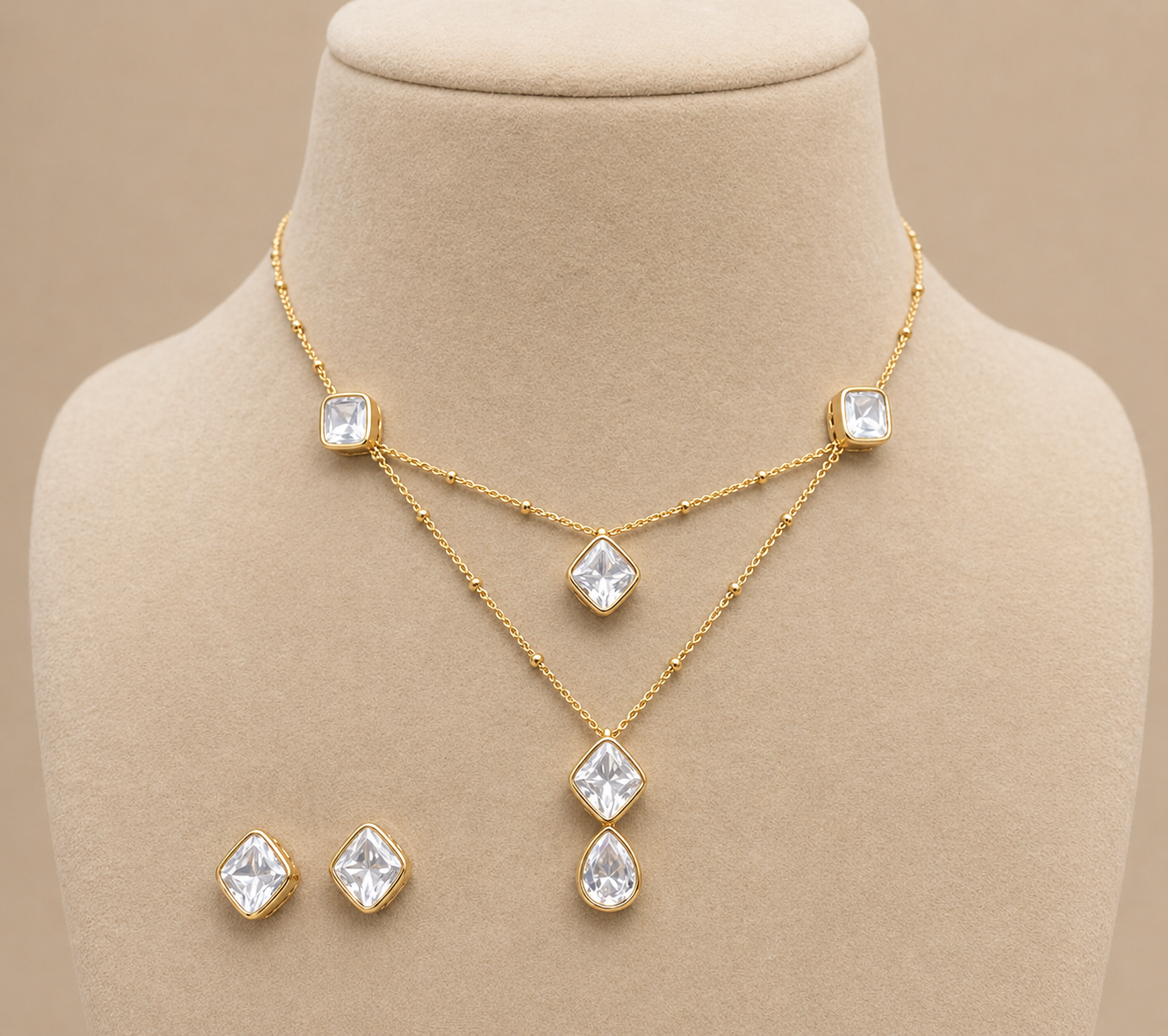 Gold necklace and earrings set on a mannequin bust with a beige background