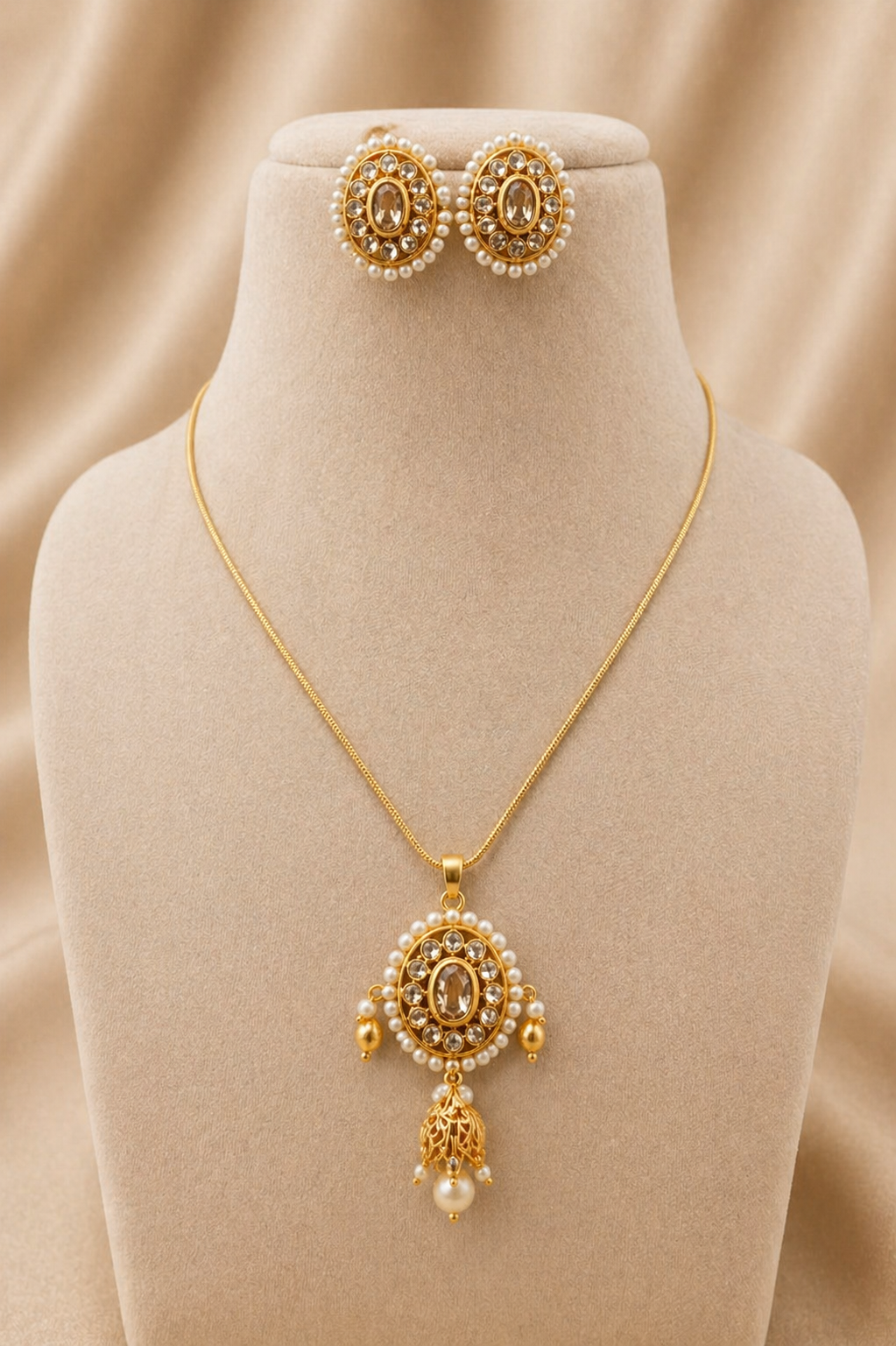 Gold necklace and earrings on a beige velvet stand with a beige background