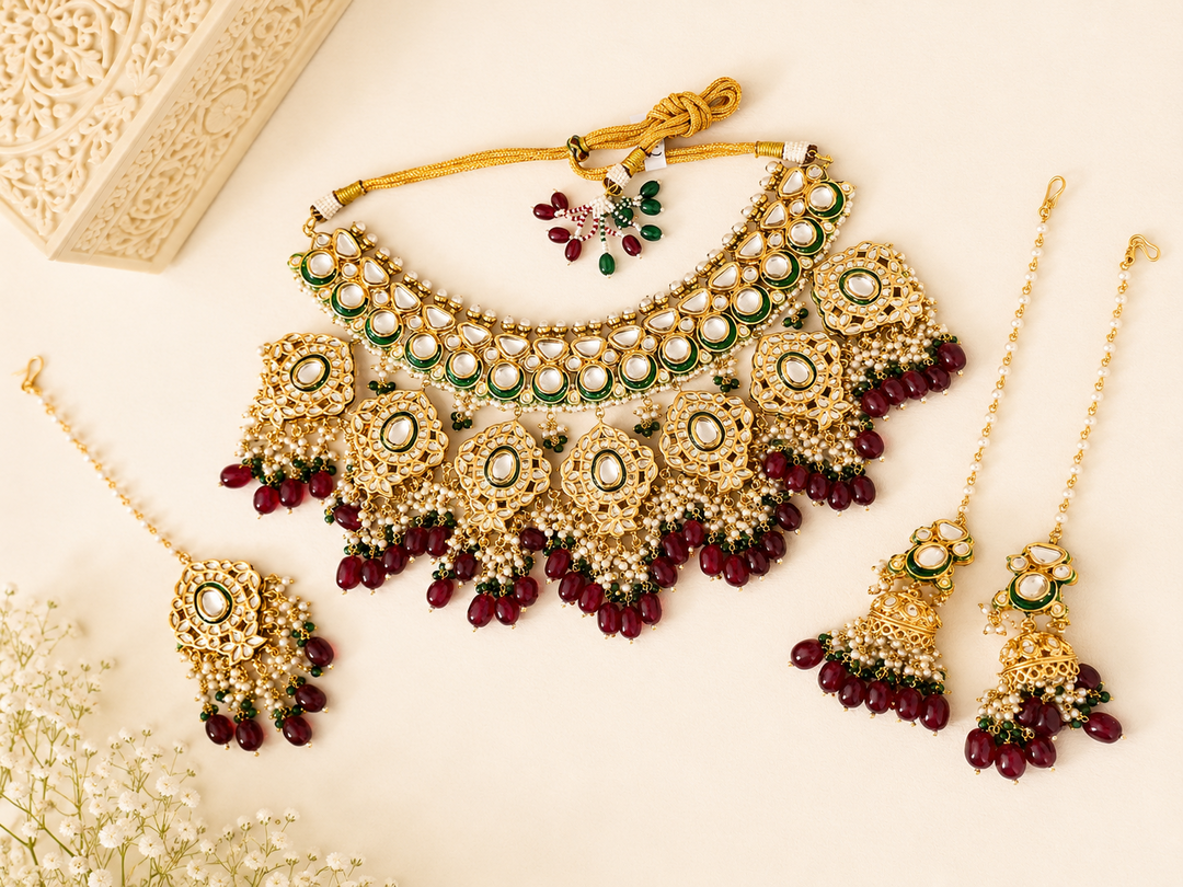 Ornate gold and green jewelry set with red beads on a light background